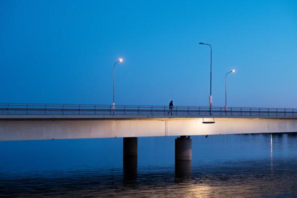 Yksinäinen sillan ylittäjä illan hämärässä