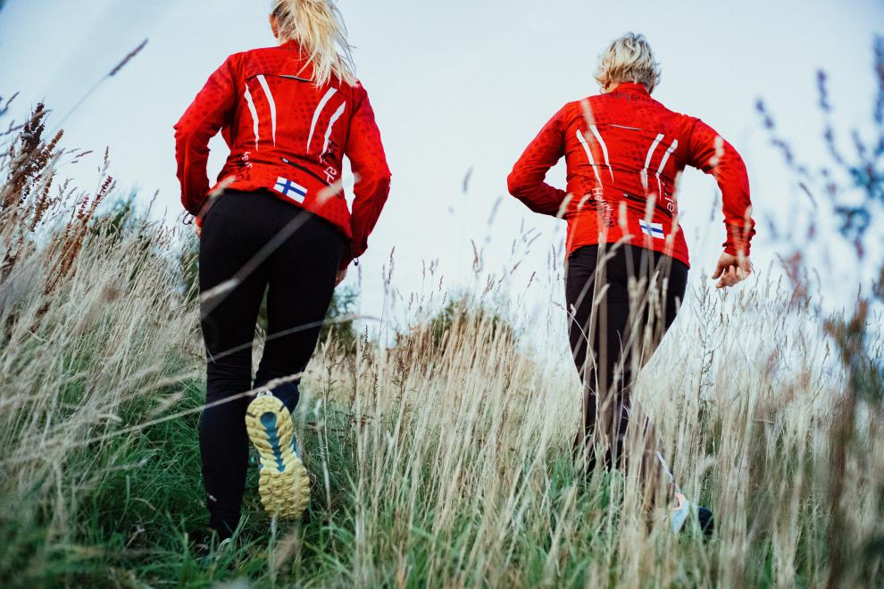 Kaksi naista lenkkeilemässä pellolla.