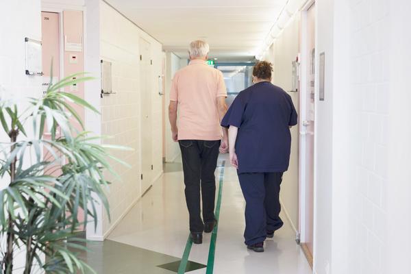 Sairaanhoitaja ja iäkäs mies kävelevät sairaalan käytävällä. Kuvaaja: Kaisa Sunimento.