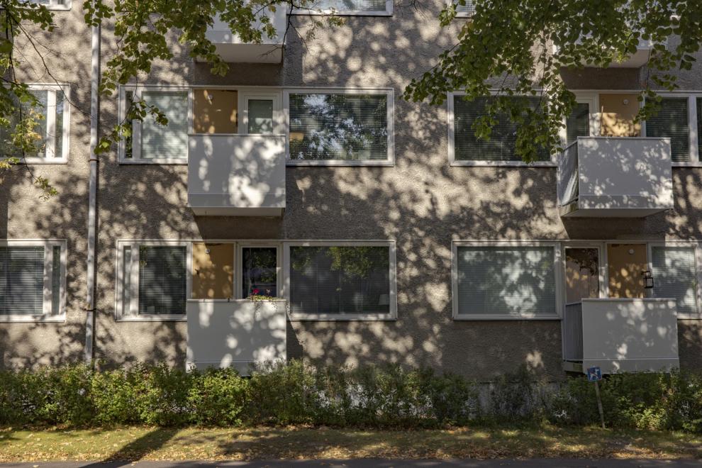 Vanhan kerrostalon parvekkeisiin heijastuu puun varjokuva.