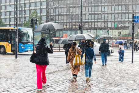 Ihmiset kävelevät sateessa Helsingin keskustassa.